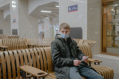 Sitting waiting for the train to leave, with a thoughtful look, a guy in a medical mask, in a public