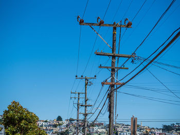 Low angle view of electricity pylon against clear blue sky