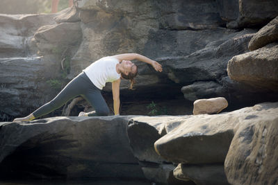 Full length of woman doing yoga on rock