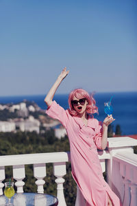 Portrait of young woman wearing sunglasses while standing against sky