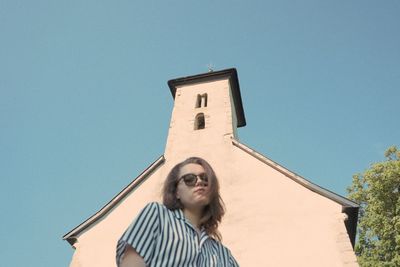 Low angle portrait of woman against building against clear sky