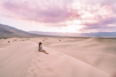 Man standing on sand dune in desert against sky