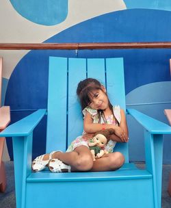 Portrait of young girl sitting on beach chair 