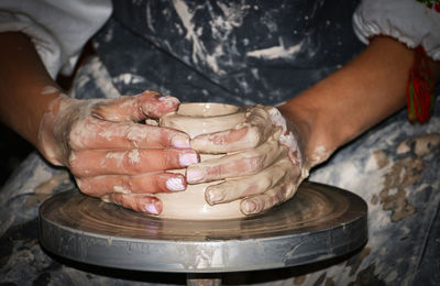 Midsection of man shaping earthenware pottery wheel 