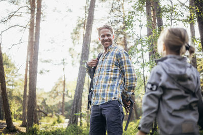 Smiling father looking at daughter in forest