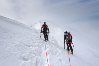 Rear view of people skiing on snowcapped mountain