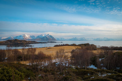 Scenic view of lake by snowcapped mountains against sky