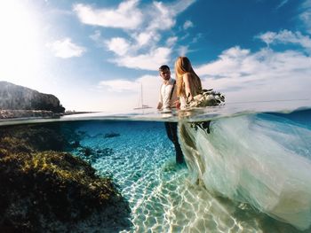 Wedding couple standing in sea against sky