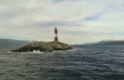 Lighthouse by sea against sky