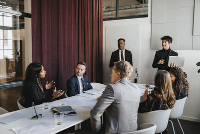 Female entrepreneur discussing with colleagues in business meeting at office