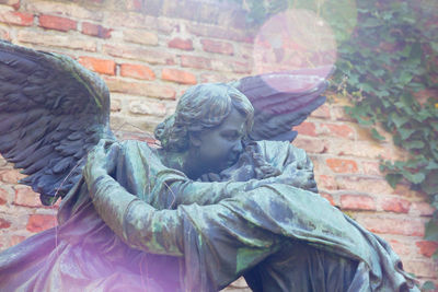 Close-up of boy statue against brick wall