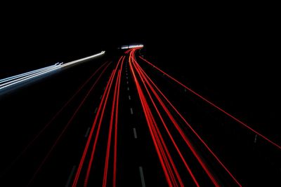 Light trails on suspension bridge against sky at night