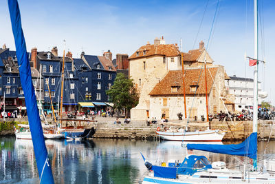 Sailboats moored on canal against buildings in city