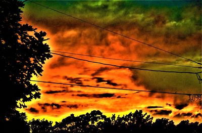 Low angle view of silhouette trees against dramatic sky