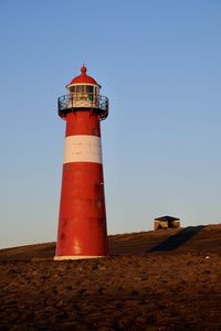 Lighthouse by sea against clear sky. 