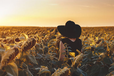 Woman in sunflower field during sunset