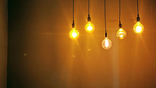 Low angle view of illuminated light bulbs hanging from ceiling