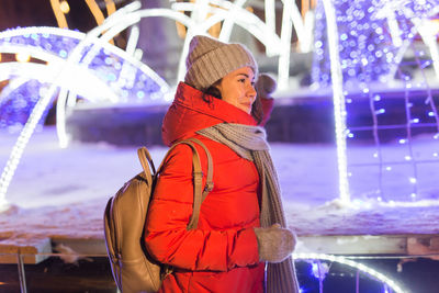 Midsection of woman standing in amusement park during winter at night
