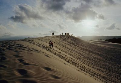 Scenic view of people riding on desert against sky