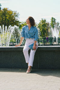 Portrait of young elegant business woman in eye glasses walking in city street with phone. urban