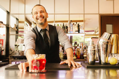 Happy bartender serving drink at counter