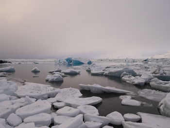 Frozen ice formations in lake against sky