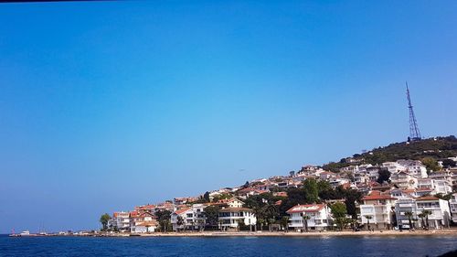 Buildings at waterfront against blue sky