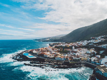 Aerial view of sea and buildings against sky