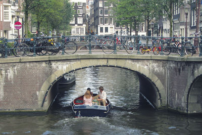 People sitting on bridge over river in city