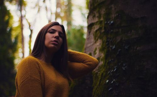 Portrait of young woman with hand in hair at forest