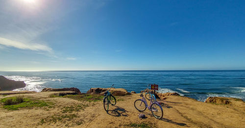 Bicycle on beach against blue sky