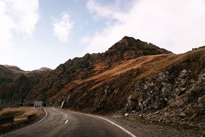 Road by mountain against sky