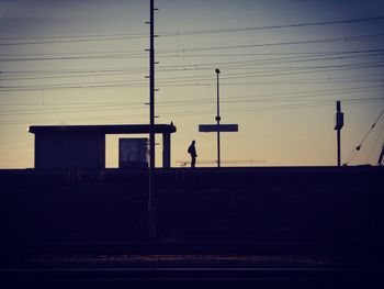 Silhouette person standing on railroad station platform at dawn