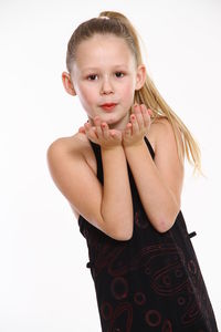 Portrait of girl blowing cupped hands against white background