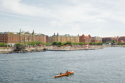 Scenic view of river in city against sky