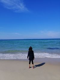 Rear view of man on beach against sky