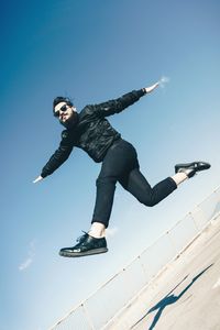 Low angle view of man jumping against clear sky