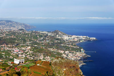 Aerial view of cityscape by sea against blue sky