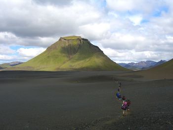 People walking on landscape against mountains