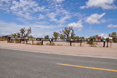 Road by trees against sky