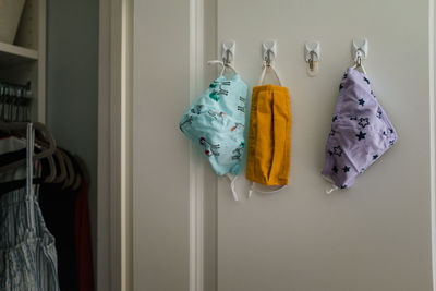 Three cloth masks hanging on hooks in closet