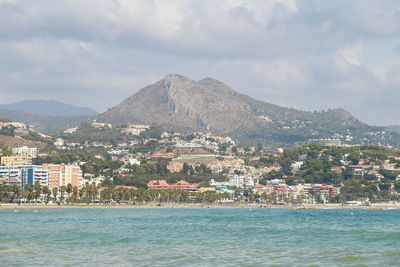 Aerial view of townscape by sea against sky