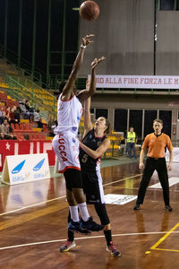 Full length of men playing with ball in background