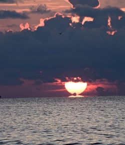 Scenic view of sea against dramatic sky during sunset