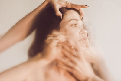 Cropped hands of people holding woman face against wall