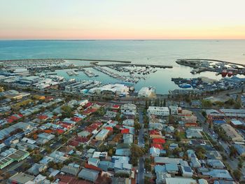 High angle view of sea by buildings against sky during sunset