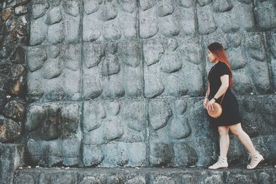 Full length of woman standing against wall