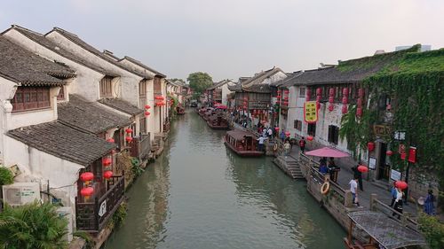 Canal amidst houses against sky in city