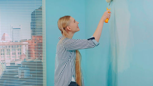 Rear view of woman with arms raised standing at home