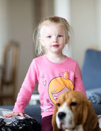 Portrait of cute girl sitting with dog at home